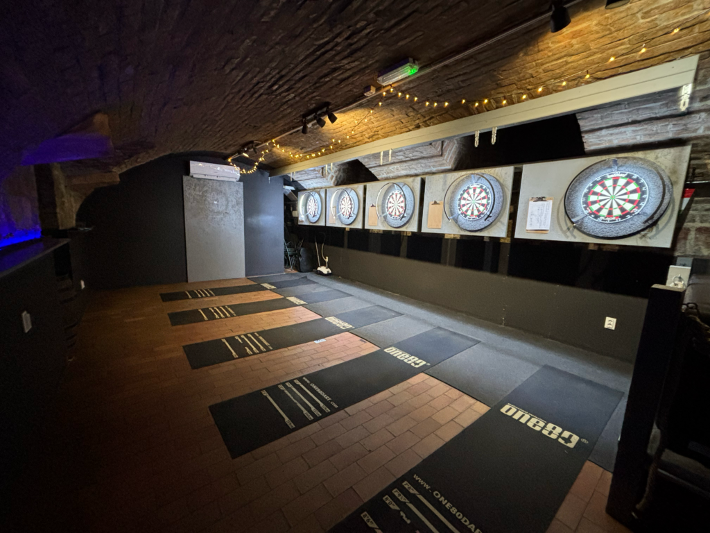 Five professional steel dart lanes in the cozy, arched interior of The Black Door Darts & Sport Bar in downtown Budapest.