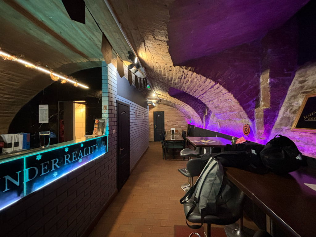 The Black Door Darts & Sport Bar has a bar counter with draft beers, a selection of drinks, and a cozy cellar.